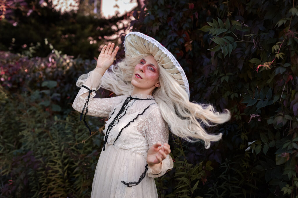 Cosplayer als Fliegenpilz verkleidet wirft die Haare der Perücke aufgeteilt in zwei Teile nach hinten über die Schulter