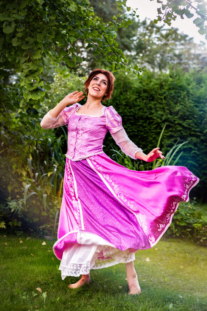 Cosplayer als Rapunzel aus Disney's Rapunzel mit kurzen braunen Haaren und wehendem Rock